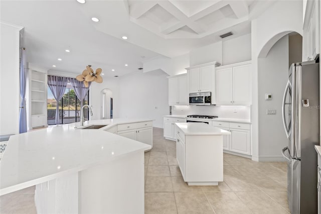 kitchen with sink, white cabinetry, appliances with stainless steel finishes, a towering ceiling, and a large island