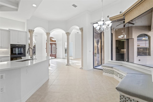 kitchen with sink, decorative light fixtures, light tile patterned floors, double oven, and decorative columns