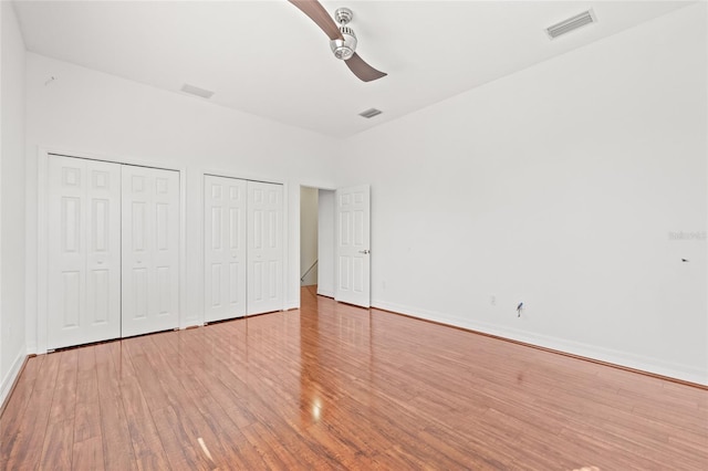 unfurnished bedroom featuring two closets, ceiling fan, and light hardwood / wood-style flooring