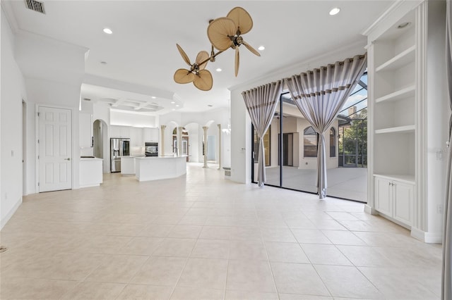 unfurnished living room with built in shelves, ceiling fan, and light tile patterned floors