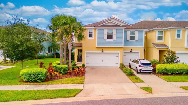 multi unit property with a garage, concrete driveway, a front lawn, and stucco siding