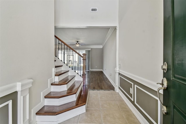 tiled foyer entrance with crown molding and ceiling fan