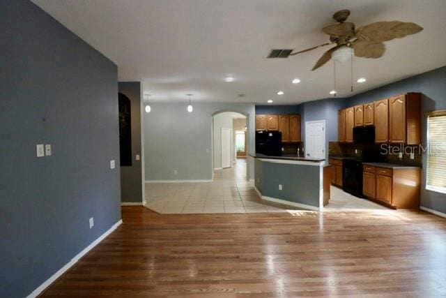 kitchen featuring decorative backsplash, black appliances, light wood-type flooring, and ceiling fan