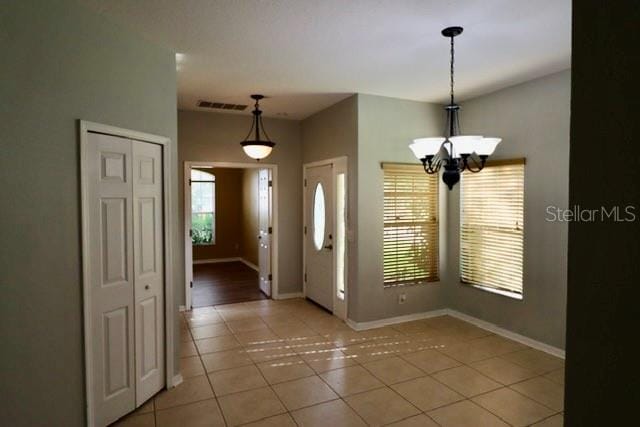 tiled foyer featuring an inviting chandelier