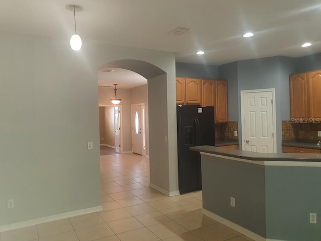 kitchen featuring backsplash, black refrigerator with ice dispenser, pendant lighting, and light tile patterned floors