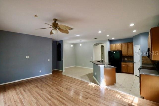 kitchen with decorative backsplash, ceiling fan, black appliances, and light hardwood / wood-style floors