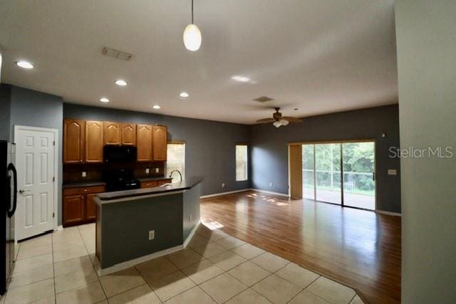 kitchen featuring black appliances, sink, light wood-type flooring, hanging light fixtures, and ceiling fan