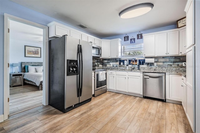 kitchen featuring light hardwood / wood-style flooring, white cabinets, light stone countertops, and stainless steel appliances