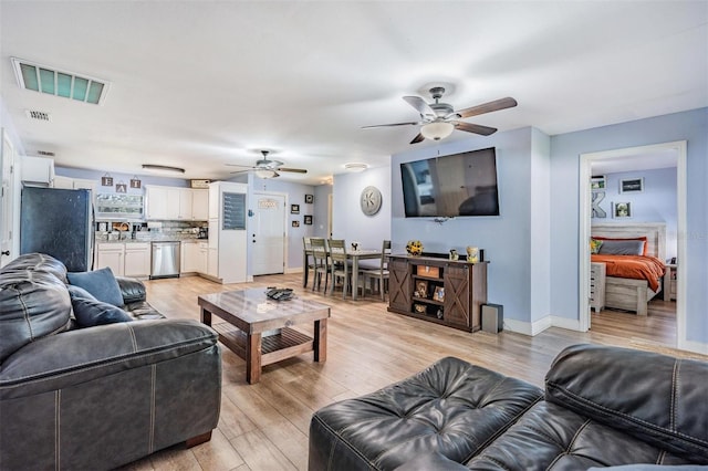 living room featuring a fireplace, light wood-type flooring, and ceiling fan