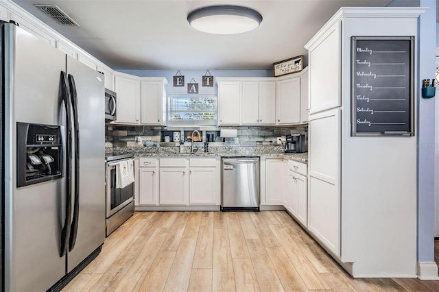 kitchen featuring light stone counters, white cabinetry, light wood-type flooring, sink, and stainless steel appliances