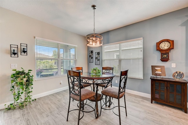 dining space with light hardwood / wood-style flooring and a notable chandelier