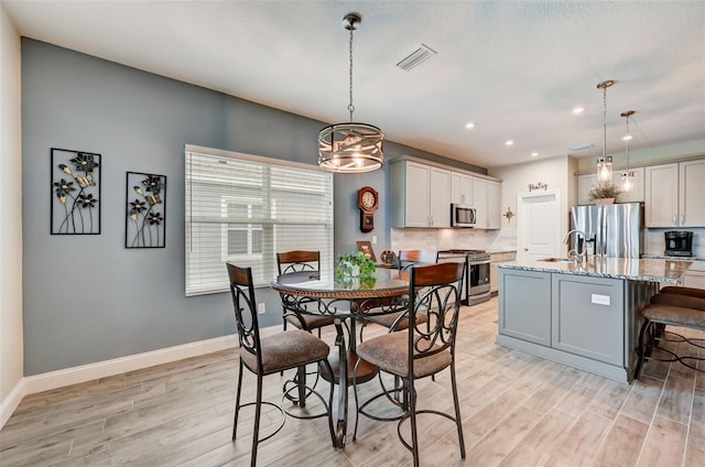 dining space featuring sink, light hardwood / wood-style floors, and a notable chandelier