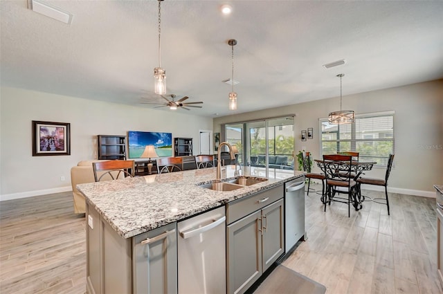 kitchen featuring dishwasher, sink, hanging light fixtures, gray cabinets, and a kitchen island with sink