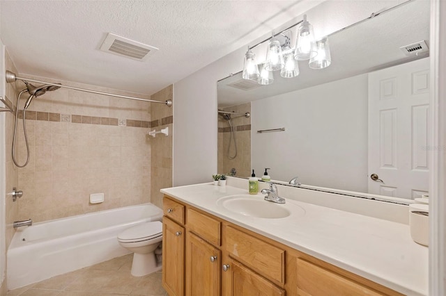 full bathroom with tiled shower / bath, a textured ceiling, toilet, vanity, and tile patterned floors