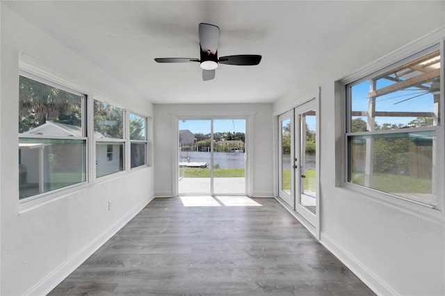 unfurnished sunroom with a water view, ceiling fan, and plenty of natural light