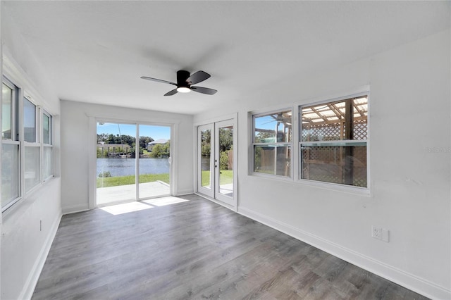 unfurnished sunroom with a water view and ceiling fan