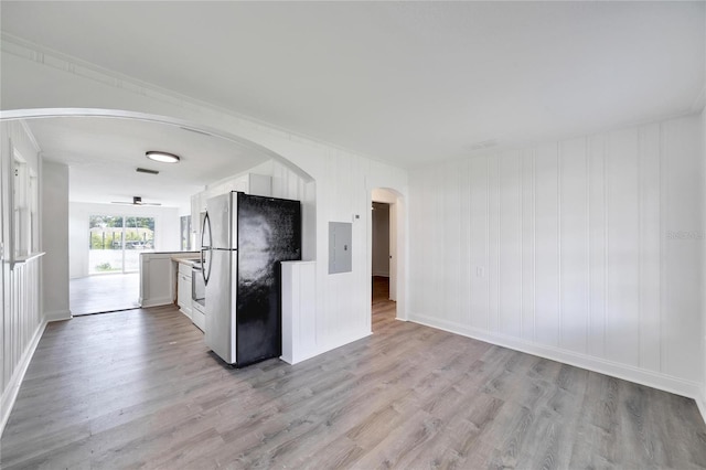 kitchen with electric panel, stainless steel refrigerator, light hardwood / wood-style flooring, and white cabinets