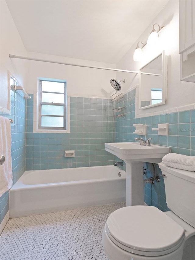 bathroom featuring tile patterned floors, toilet, tiled shower / bath, and tile walls