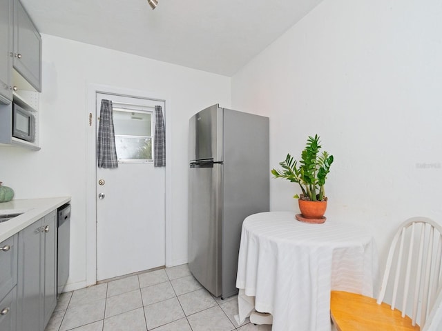 kitchen with gray cabinets, appliances with stainless steel finishes, and light tile patterned floors