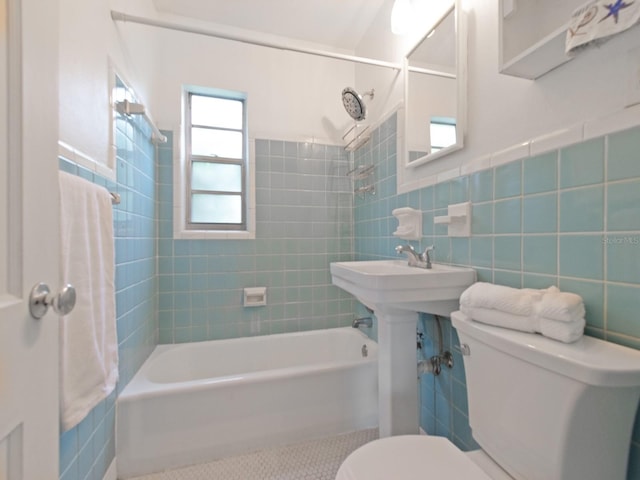 bathroom with toilet, tile walls, and tiled shower / bath combo