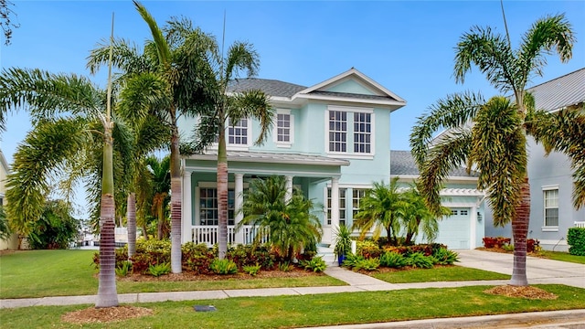 coastal inspired home with covered porch, a garage, and a front lawn