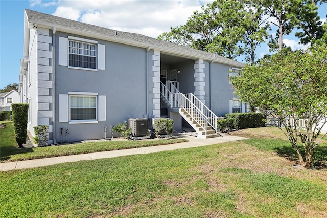 rear view of house featuring a lawn and central AC unit