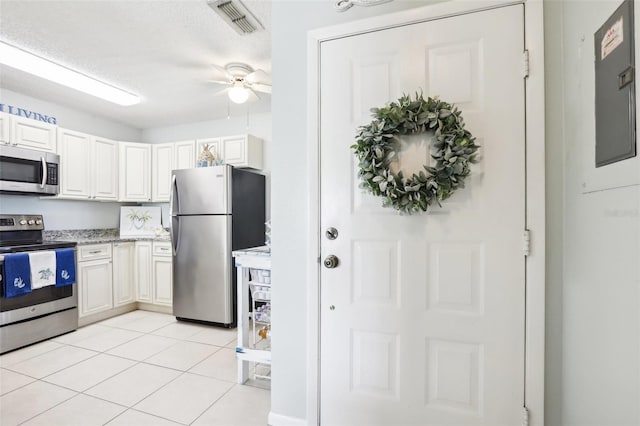 kitchen featuring appliances with stainless steel finishes, ceiling fan, white cabinets, and light tile patterned floors