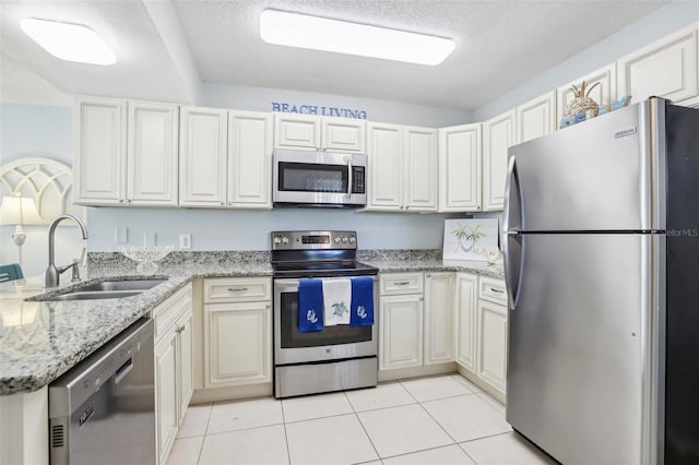 kitchen with white cabinetry, light stone countertops, appliances with stainless steel finishes, and sink