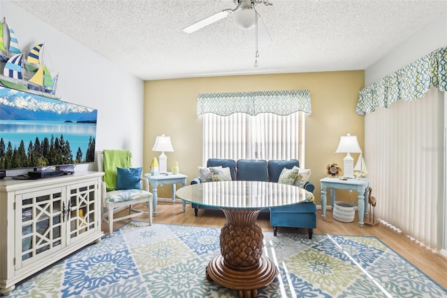 living area with a textured ceiling, hardwood / wood-style flooring, and ceiling fan