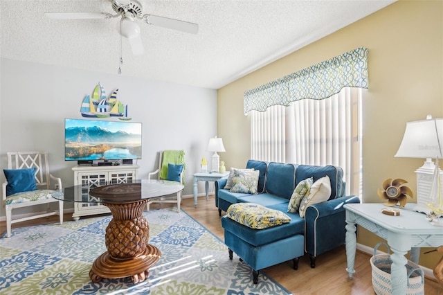 living room featuring a textured ceiling, wood-type flooring, and ceiling fan