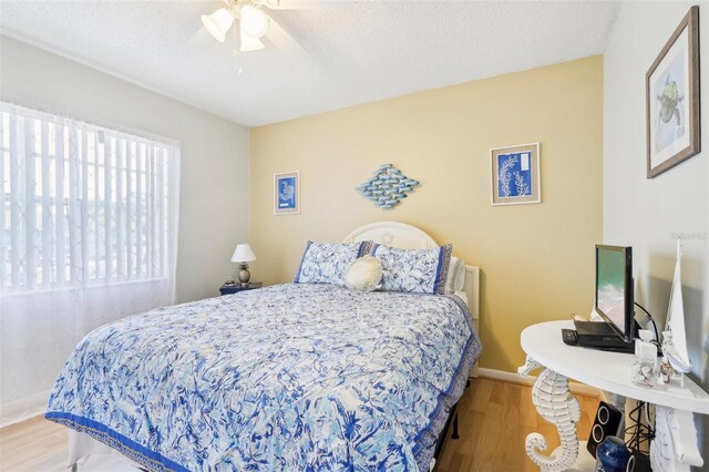 bedroom with ceiling fan, a textured ceiling, and hardwood / wood-style floors