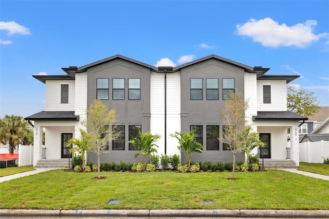 view of front facade with fence, a front lawn, and stucco siding