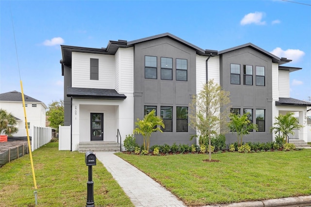 view of front facade with a front yard, fence, and stucco siding