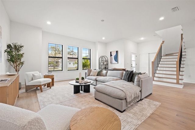 living room featuring stairway, visible vents, light wood finished floors, and recessed lighting