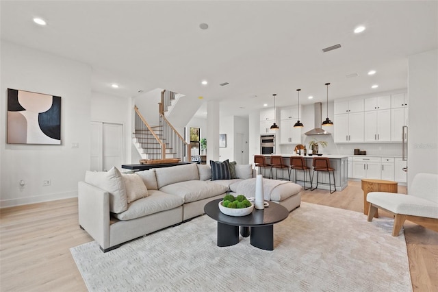 living area featuring stairs, light wood-style flooring, visible vents, and recessed lighting