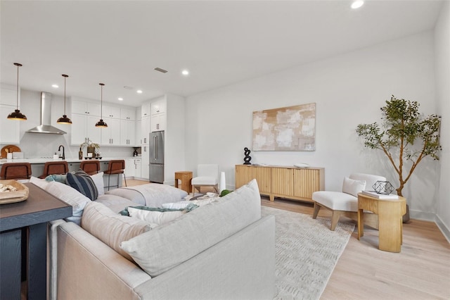 living area featuring light wood finished floors, visible vents, baseboards, radiator, and recessed lighting