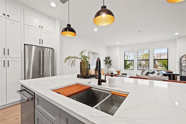 kitchen with a sink, appliances with stainless steel finishes, decorative light fixtures, and recessed lighting