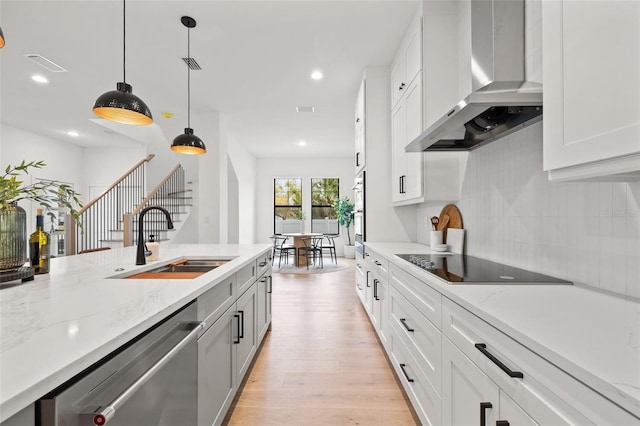 kitchen with visible vents, wall chimney exhaust hood, light wood-style flooring, appliances with stainless steel finishes, and a sink