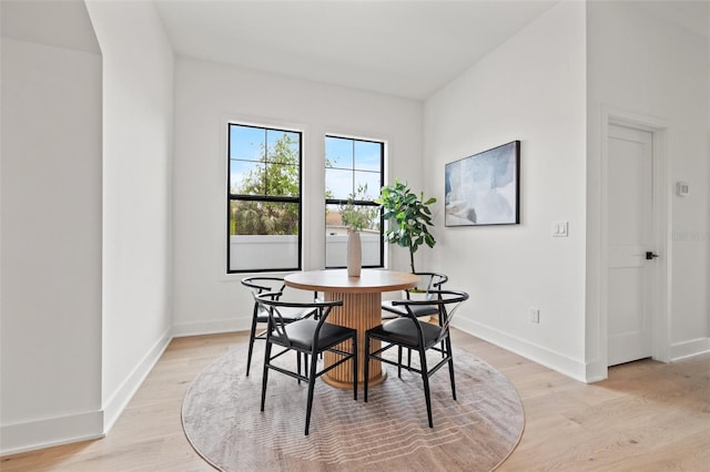 dining space with light wood-type flooring and baseboards