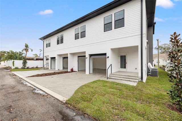 view of front of property with driveway, a garage, central AC unit, fence, and a front lawn