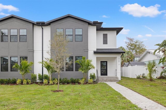 view of front of home with fence, a front lawn, and stucco siding