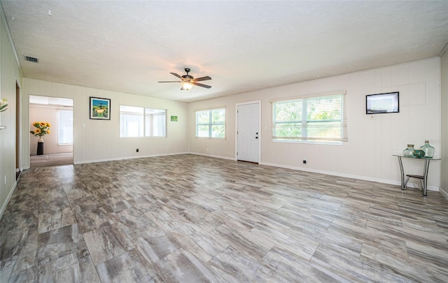 unfurnished living room with light wood-type flooring, a textured ceiling, and ceiling fan