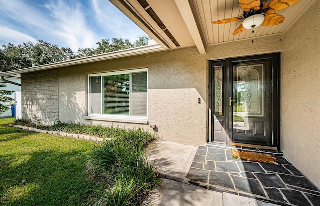 property entrance featuring a yard and ceiling fan