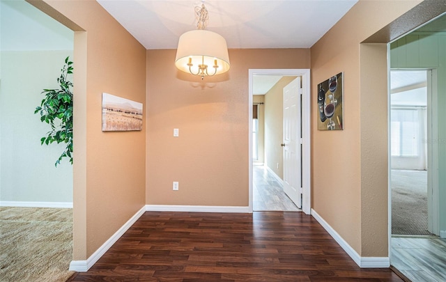 hall with dark hardwood / wood-style flooring and an inviting chandelier