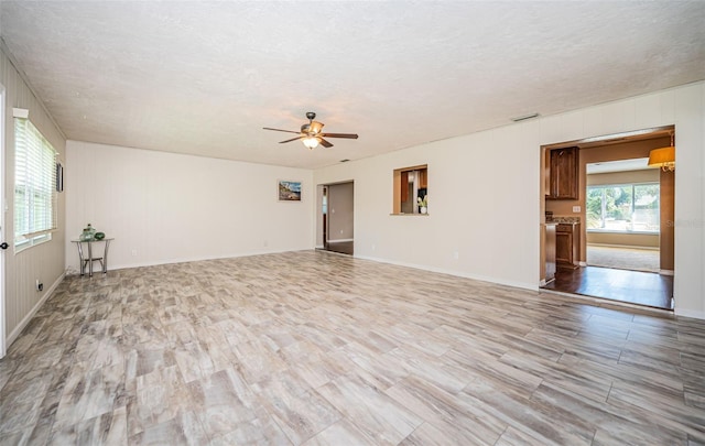 unfurnished room with ceiling fan, light wood-type flooring, and a textured ceiling