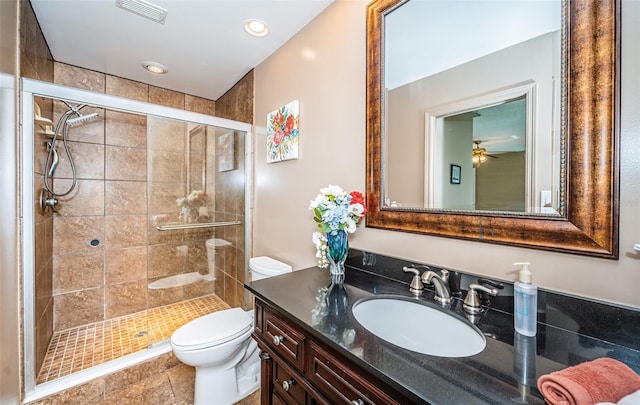 bathroom with ceiling fan, vanity, an enclosed shower, and toilet