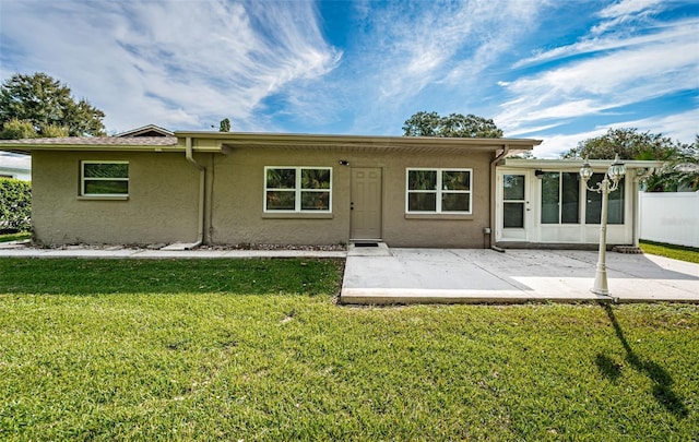 back of property with a lawn and a patio