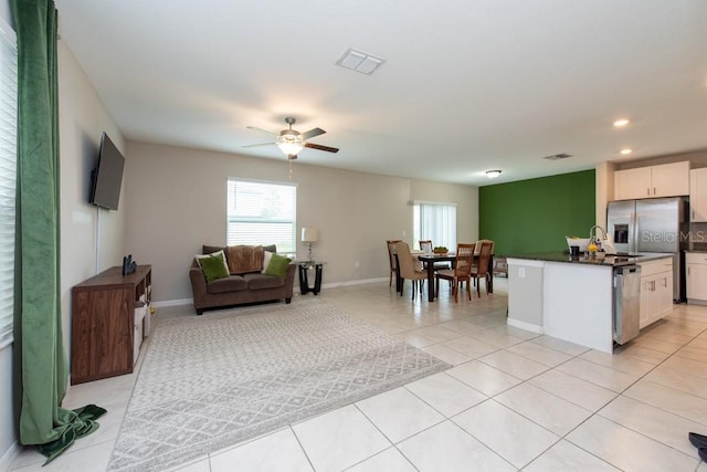 kitchen with stainless steel dishwasher, ceiling fan, white cabinetry, a kitchen island, and light tile patterned flooring