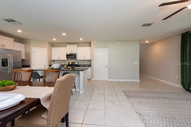 tiled dining area featuring a textured ceiling, ceiling fan, and sink