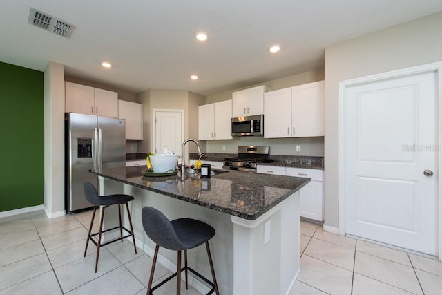 kitchen featuring stainless steel appliances, a kitchen island with sink, sink, white cabinetry, and light tile patterned flooring